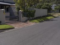 a white house with a metal fence and gate sits on the side of a road