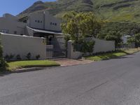 a white house with a metal fence and gate sits on the side of a road