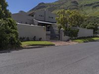 a white house with a metal fence and gate sits on the side of a road