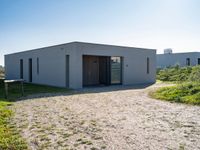 this is a small building with doors on the side in a field with grass and shrubs