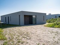 this is a small building with doors on the side in a field with grass and shrubs