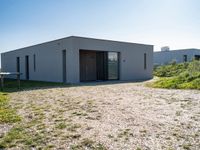 this is a small building with doors on the side in a field with grass and shrubs