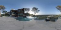 the outside of a house with a huge pool and a view of the hills on the horizon