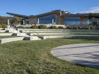 a large house with concrete steps leading to a lawn area outside of the building and stairs are set up next to the grass