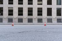 traffic cones are standing in front of the entrance to a building on the street in an empty area