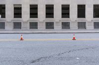 traffic cones are standing in front of the entrance to a building on the street in an empty area