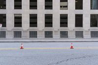 traffic cones are standing in front of the entrance to a building on the street in an empty area