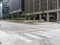 an empty street that has been paved with white lines in between buildings and trees, the cars are in the foreground