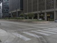 an empty street that has been paved with white lines in between buildings and trees, the cars are in the foreground