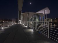 a building and its walkway near a river at night and illuminated up with lights in the dark