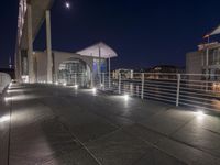 a building and its walkway near a river at night and illuminated up with lights in the dark