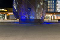 the modern architecture is being illuminated with blue lighting and a fire hydrant in front