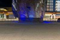 the modern architecture is being illuminated with blue lighting and a fire hydrant in front