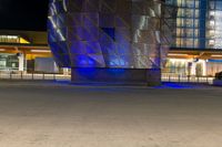 the modern architecture is being illuminated with blue lighting and a fire hydrant in front