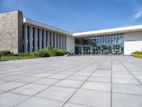 there is a large courtyard with multiple tall windows and benches in front of the building