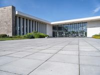 there is a large courtyard with multiple tall windows and benches in front of the building