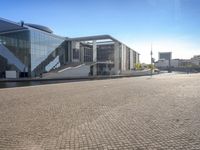 the large glass building stands at the end of the street and overlooks the river