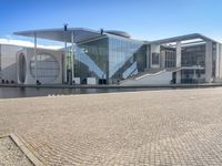 the large glass building stands at the end of the street and overlooks the river