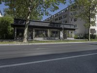 two cars are parked on a busy street in front of a building with trees and grass