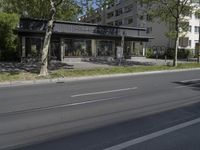 two cars are parked on a busy street in front of a building with trees and grass