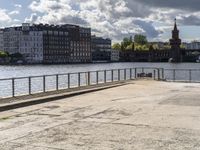 a body of water near some buildings and people on a bench in front of it