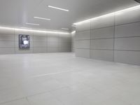 a white floor has tile and lights lit by recesses in an empty room on the wall