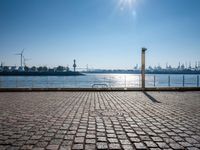 this is a street sign on a brick sidewalk next to the water and some large ships