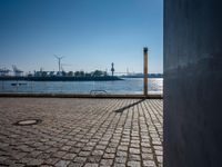 this is a street sign on a brick sidewalk next to the water and some large ships