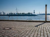 this is a street sign on a brick sidewalk next to the water and some large ships