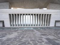a building with many columns and pillars, made of concretes, has a stone floor and ceiling