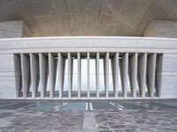 a building with many columns and pillars, made of concretes, has a stone floor and ceiling