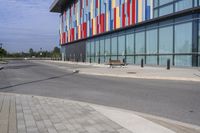 a red stop sign is at the end of an empty sidewalk and outside a building