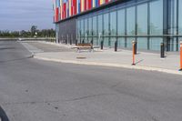 a red stop sign is at the end of an empty sidewalk and outside a building