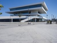 an empty parking lot in front of a building with curved glass windows and stairs on the ground