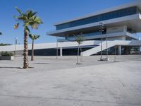 an empty parking lot in front of a building with curved glass windows and stairs on the ground