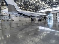 a plane sits in a large hanger at the airport while being serviced for service