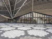 a black and white tile floor in front of a modern building with triangular windows and geometric ceiling