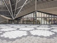 a black and white tile floor in front of a modern building with triangular windows and geometric ceiling