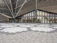 a black and white tile floor in front of a modern building with triangular windows and geometric ceiling