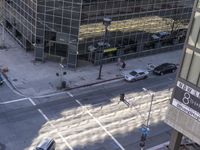 a couple cars are going by a tall building and some buildings that have been constructed around it