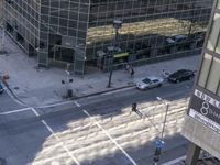 a couple cars are going by a tall building and some buildings that have been constructed around it