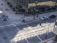 a couple cars are going by a tall building and some buildings that have been constructed around it