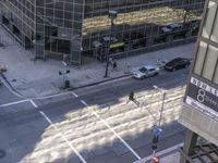 a couple cars are going by a tall building and some buildings that have been constructed around it