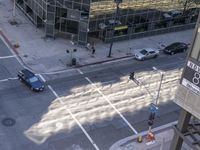 a couple cars are going by a tall building and some buildings that have been constructed around it