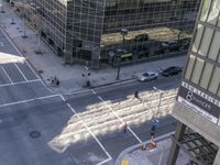 a couple cars are going by a tall building and some buildings that have been constructed around it