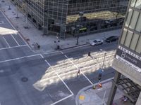 a couple cars are going by a tall building and some buildings that have been constructed around it