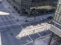 a couple cars are going by a tall building and some buildings that have been constructed around it