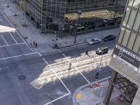 a couple cars are going by a tall building and some buildings that have been constructed around it