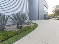 a concrete walkway that leads to a garage and a flowerbed at the side of the house