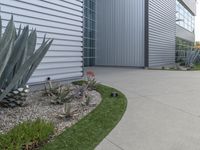 a concrete walkway that leads to a garage and a flowerbed at the side of the house